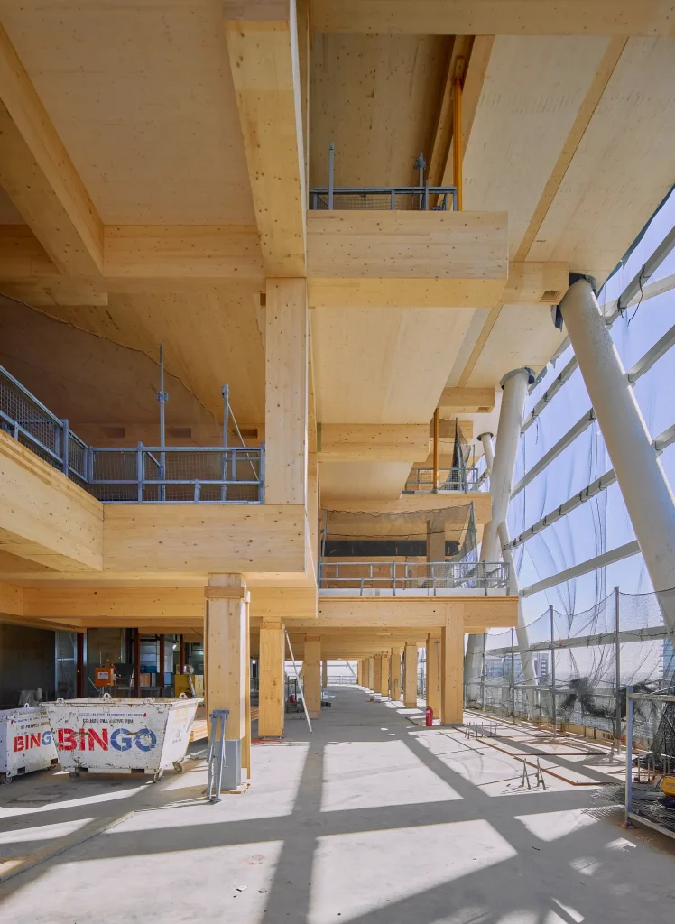 Interior de un edificio en construcción con estructura de madera laminada y vigas de madera estructural